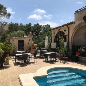 un patio con mesas y sillas y una piscina en Villa Lorenzo, en Cala Figuera