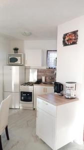 eine Küche mit weißen Schränken und einem weißen Kühlschrank in der Unterkunft Apartments Happy Day in Karlobag