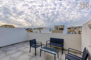 un patio con 2 sillas y una mesa en el techo en A fully equipped 3BR penthouse with large terrace by 360 Estates, en Il-Gżira