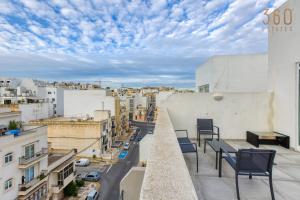 a balcony with chairs and a view of a city at A fully equipped 3BR penthouse with large terrace by 360 Estates in Il-Gżira