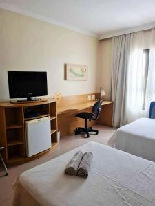 Habitación de hotel con 2 camas y escritorio con TV. en ELEGANCE SUÍTES FRANCA en Franca
