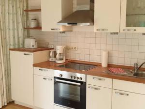 a kitchen with white cabinets and a stove top oven at Deichgräfin 1 in Horumersiel