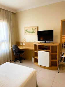Habitación de hotel con escritorio, TV y cama en ELEGANCE SUÍTES FRANCA en Franca
