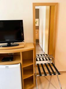 Habitación con escritorio, TV y silla. en ELEGANCE SUÍTES FRANCA en Franca