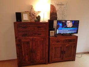 a television on a wooden stand with a wooden dresser at Deichgräfin 3 in Horumersiel +8 photos