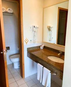 um banheiro com uma pia, um vaso sanitário e um espelho em ELEGANCE SUÍTES FRANCA em Franca