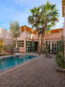 a house with a swimming pool and palm trees at Riad tania mozaik in Taroudant