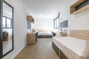 a bedroom with a bed and a desk and a sink at Micampus Getafe II Student Residence in Getafe