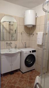 ein Badezimmer mit einer Waschmaschine neben einem Waschbecken in der Unterkunft Apartments Happy Day in Karlobag