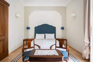 ソレントにあるRosa Magra Guest Houseのベッドルーム1室(青いヘッドボード付きのベッド1台、椅子2脚付)