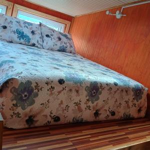 a bed with a floral comforter in a room at Tyni house in Puerto Natales