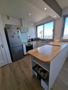 a kitchen with a refrigerator and a wooden counter top at Le Landouzy - Parking - Netflix - Wifi in Chamalières
