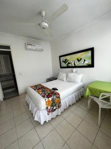 Hotel Zamba في جيراردو: غرفة نوم بسرير ابيض وبطانية خضراء