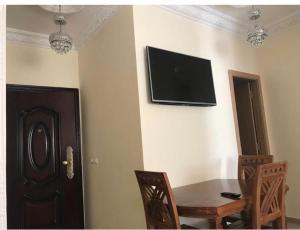 Habitación con mesa y TV en la pared. en Appartement Familial en face la plage Haouara Tanger, en Tánger