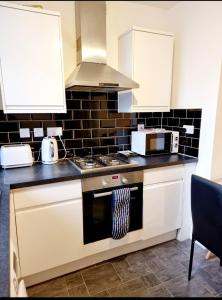 a kitchen with a stove and a microwave at Stylish 2 Bedroom Apartment Sleeps 5 - 3 mins walk to Mile End Station in London