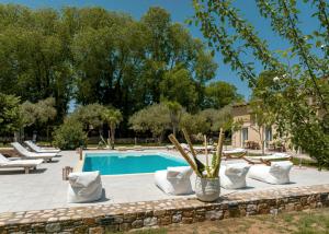 een zwembad met witte ligstoelen en een zwembad bij Natura villa with jacuzzi in Limenas