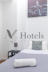 a white bedroom with a bed with a hotel sign on it at A&Z Luis Cabrera-Auto check-in property in Madrid