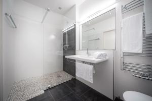 uma casa de banho branca com um lavatório e um espelho em CityFlat 38 Schladming by globboard em Schladming