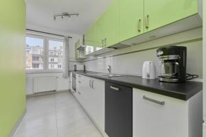 a kitchen with green and white cabinets and a counter top at Cozy Apartment Klimasa with Balcony in Wrocław by Renters in Wrocław