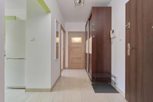 a hallway with white walls and a wooden door at Cozy Apartment Klimasa with Balcony in Wrocław by Renters in Wrocław