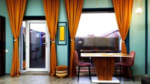 ein Esszimmer mit orangefarbenen Vorhängen sowie einem Tisch und Stühlen in der Unterkunft Mogosoaia High Living Apartment in Chitila
