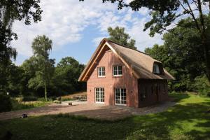 uma casa de tijolos vermelhos com um telhado de gambrel em Exklusives Reetdachhaus in der Bremer Schweiz em Bremen-Vegesack