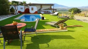 einen Garten mit Pool und Stühlen und ein Haus in der Unterkunft Casa de la Vida Málaga in Pizarra
