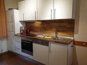 a kitchen with white cabinets and a sink at Ferienhaus Jantje Moe 4 in Horumersiel