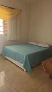 um quarto com uma cama com um cobertor azul em Escarpas do Lago em Capitólio