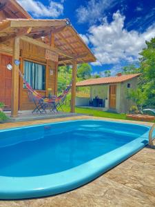 una piscina con una hamaca y una casa en Recanto da Tia Juju, en Santa Teresa