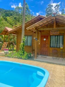 una casa de madera con piscina frente a ella en Recanto da Tia Juju, en Santa Teresa