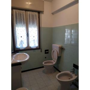 een badkamer met een wastafel, een toilet en een wastafel bij Bright villa with private garden - Beahost Rentals in Caorle
