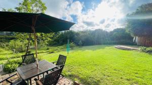 una mesa de picnic con una sombrilla en el césped en Zens Paradise Self Catering Cottage, en Wittedrif