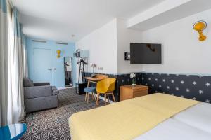 パリにあるオテル オーガスティン アストテルのベッド、ソファ、デスクが備わるホテルルームです。