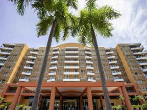 zwei Palmen vor einem Gebäude in der Unterkunft Resort Style Escape King Bed Pool Balcony in Darwin