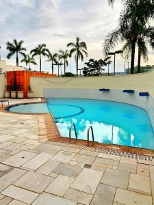 uma grande piscina com palmeiras ao fundo em ELEGANCE SUÍTES FRANCA em Franca