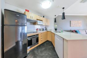 eine Küche mit einem Kühlschrank und Schränken aus Edelstahl in der Unterkunft Resort Style Escape King Bed Pool Balcony in Darwin