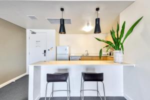 a kitchen with a white counter and stools at Resort Style City View King Bed Pool Balcony in Darwin