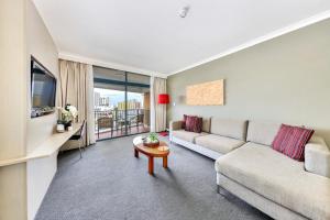 a living room with a couch and a table at Resort Style City View King Bed Pool Balcony in Darwin