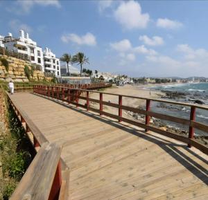 een houten promenade naast een strand met gebouwen bij Sun Love calypso in Mijas