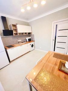 a kitchen with white cabinets and a wooden table at Go to Aibike in Promyshlennyy