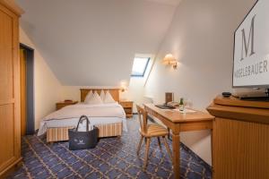 バート・ザンクト・レオンハルト・イム・ラヴァントタールにあるHotel Moselebauerのベッドとデスクが備わるホテルルームです。