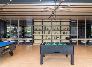 a room with a ping pong table in front of a library at Ideo O2 BTS Bangna in Bangkok