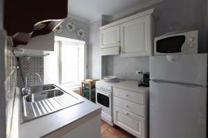 La cuisine est équipée de placards blancs et d'un réfrigérateur blanc. dans l'établissement Castello e Borgo di Porciano, à Pratovecchio