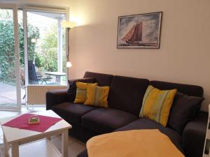 ein Wohnzimmer mit einem schwarzen Sofa und gelben Kissen in der Unterkunft Rosenhus 2 in Horumersiel
