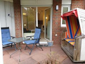 eine Terrasse mit 2 Stühlen, einem Tisch und einem Sofa in der Unterkunft Rosenhus 2 in Horumersiel