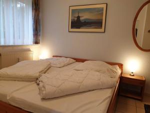 ein Bett in einem Schlafzimmer mit 2 Lampen und einem Spiegel in der Unterkunft Rosenhus 2 in Horumersiel