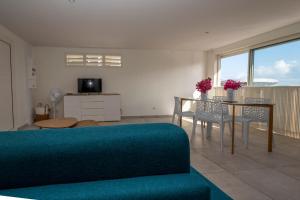 a living room with a couch and a table with chairs at ILET TURQUOISE in Le Gosier