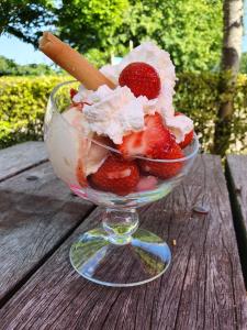 a bowl of ice cream and strawberries on a wooden table at Stacaravan op camping De Peelweide in Grashoek