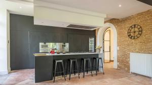 uma cozinha com um balcão com bancos de bar em Splendide Villa - Chateau Soules - Piscine Chauffée à débordement et Parc em Lavaur